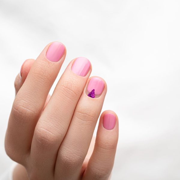 female-hands-with-pink-nail-design-white-fabric-background